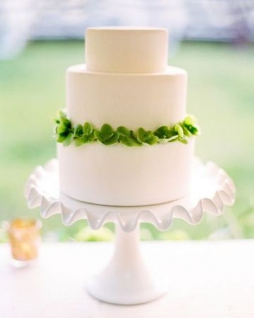a white wedding cake decorated with fresh greenery looks bold, cool and chic and will be a nice idea for a spring or summer wedding