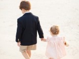 a flower girl in a short light pink dress and a ring bearer in a black blazer and tan shorts for ultimate cuteness