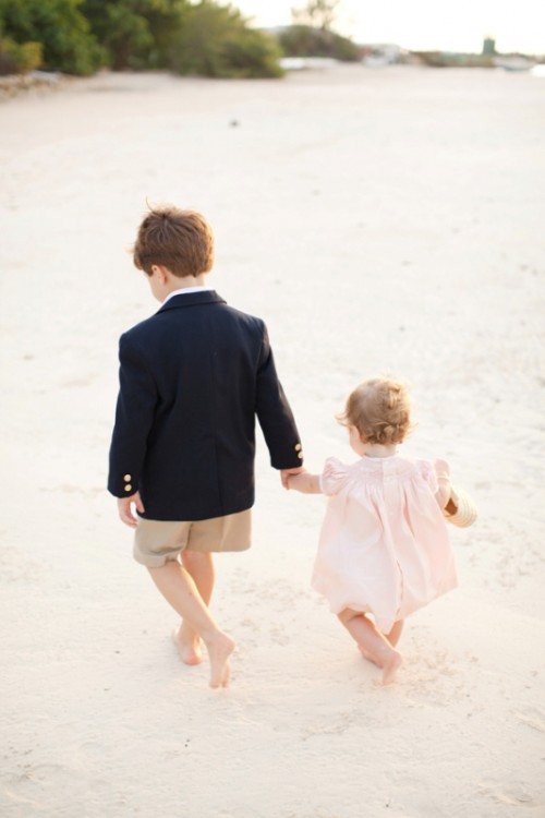 a flower girl in a short light pink dress and a ring bearer in a black blazer and tan shorts for ultimate cuteness