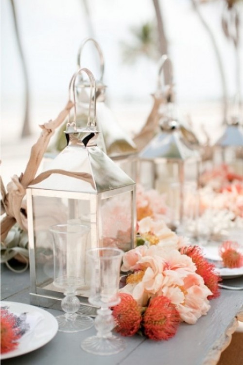 a bold beach wedding tablescape with driftwood, candles, bright blooms, air plants and glasses