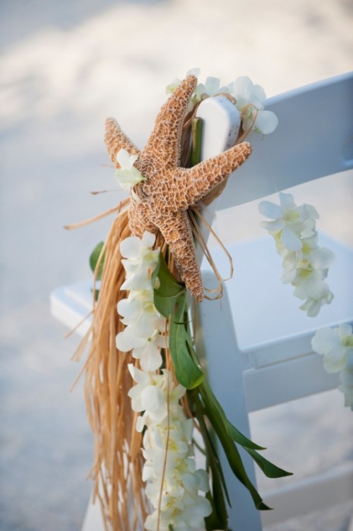 accent wedding chairs with white orchids, greenery and a starfish to make them look tropical and beach like