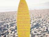 a bright yellow surf board as a beach wedding menu is a fun and beach-infused idea for your decor