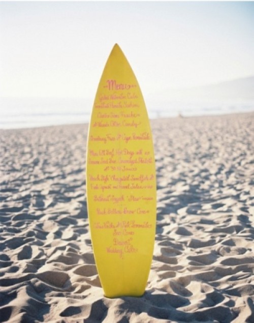 a bright yellow surf board as a beach wedding menu is a fun and beach infused idea for your decor