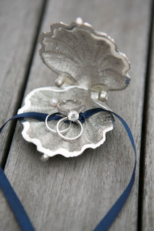a grey seashell with rings and a blue ribbon is a nice substitution for a usual wedding pillow