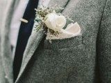 a grey woolen jacket with a black tie and a white flower boutonniere for a stylish and casual groom’s look