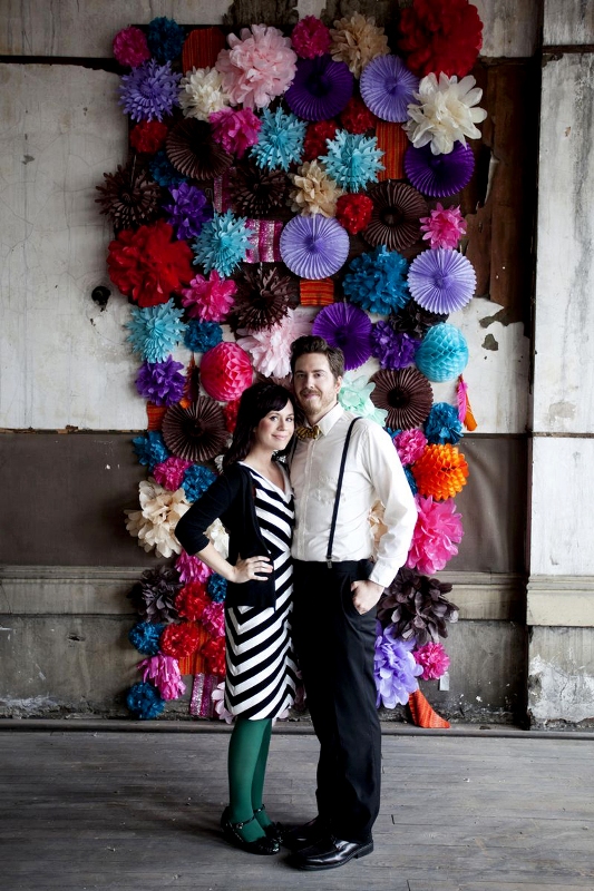 a colorful paper fan and pompom wedding backdrop is a great idea for a bright and cool wedding, it can be easily DIYed