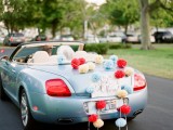 long colorful paper pompoms attached to the car are a cool substitution for usual tin can garlands