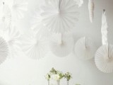 white paper fans over the tablescape are a cool decoration for a wedding, they add interest and a cool touch to the space
