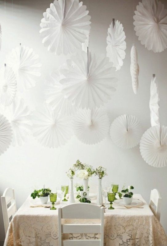 white paper fans over the tablescape are a cool decoration for a wedding, they add interest and a cool touch to the space