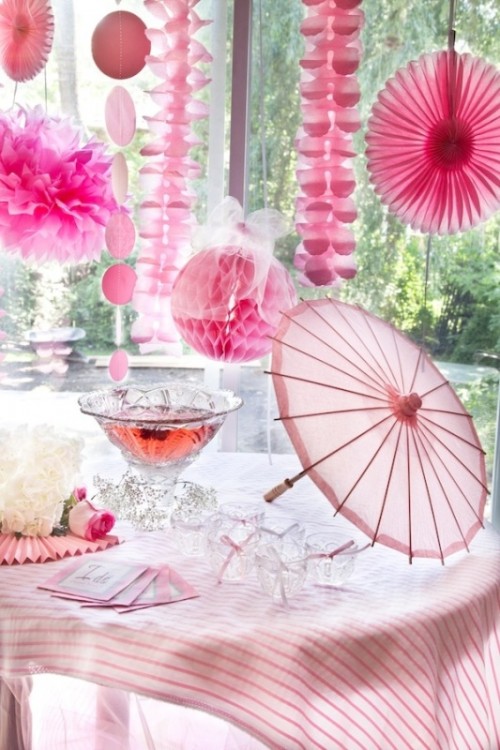 pink paper fans, pompoms and garlands over the pink punch table is a refined idea to add a touch of color to the space