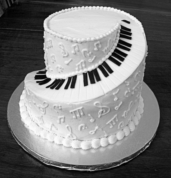 A black and white wedding cake showing off piano key buttons and notes on its sides