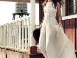 a vintage-inspired wedding dress with a sleeveless lace bodice, a pleated maxi skirt, booties and a cowboy hat for a vintage elopement