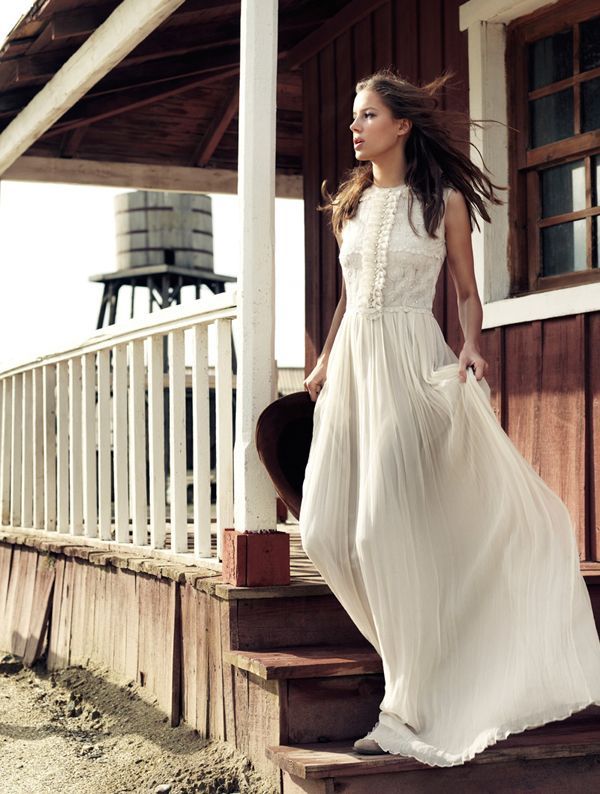 A vintage inspired wedding dress with a sleeveless lace bodice, a pleated maxi skirt, booties and a cowboy hat for a vintage elopement