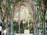 a garden wedding aisle with trees interweaving each other above creating a dome and decorated with string lights is a beautiful and fairy-tale inspired idea