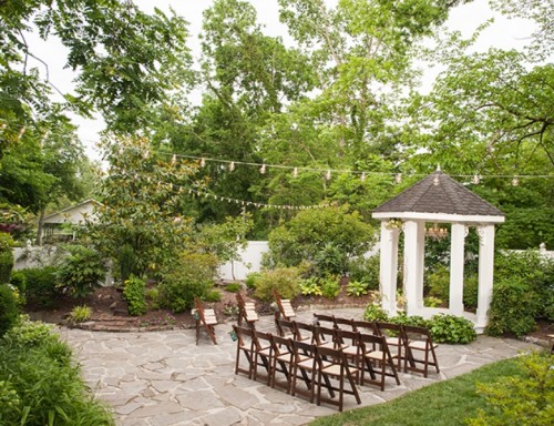 a simple and lovely garden wedding ceremony space with greenery and lights, with a chuppah and string lights is a lovely space to tie the knot