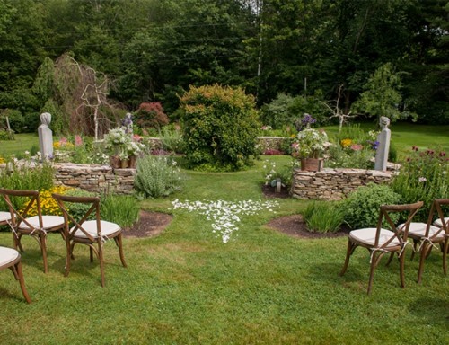 a garden wedding space for an informal ceremony, with greenery and blooms, neutral chairs is a cozy and lovely space