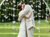 an arch covered with greenery and with paper crane garlands hanging down symbolizes happiness and love