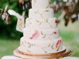 a white wedding cake with bold birds and branches painted on it looks bright and catchy and will easily match many weddings