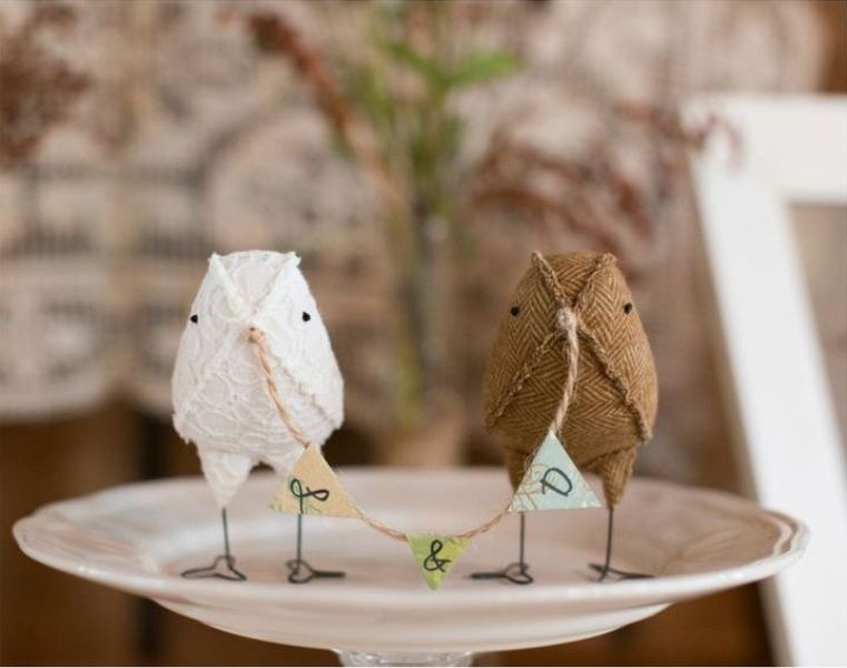 A fun DIY cake topper of two fabric birds holding a banner is a cool and lovely idea for a rustic wedding