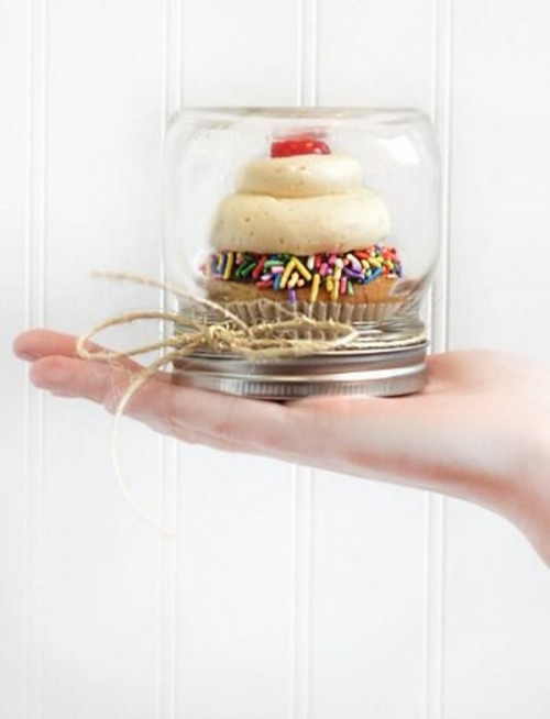 a cupcake with glazing and a berry on top in a jar is a delicious rehearsal dinner or wedding favor idea