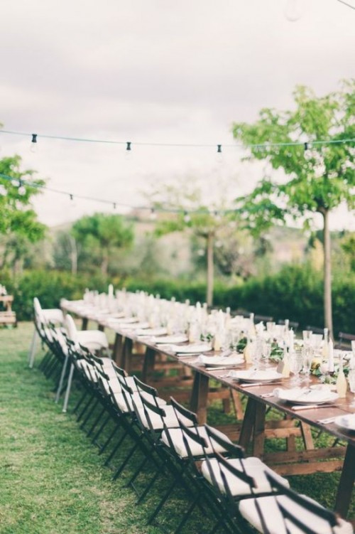 an uncovered table with greenery, lemons and candles for a chic yet relaxed Tuscany wedding