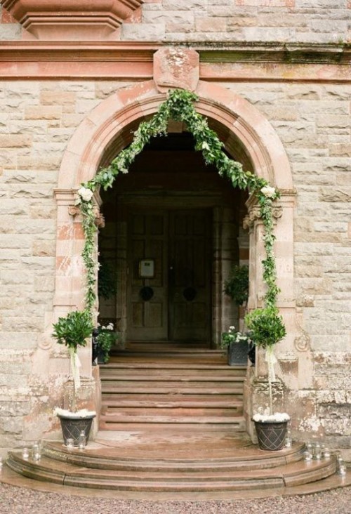 decorate the entrance with greenery garlands and potted greenery and put candles on the steps