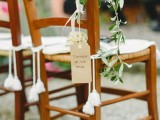 decorate wedding chairs with greenery, tags and tassels and some lovely neutral blooms to make them look cool