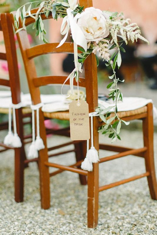 Decorate wedding chairs with greenery, tags and tassels and some lovely neutral blooms to make them look cool