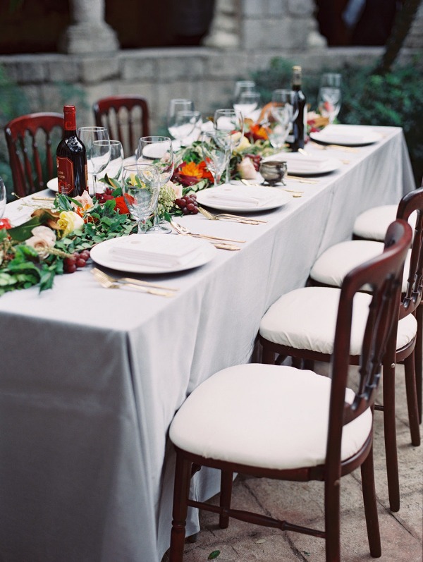 A gorgeous Italian wedding tablescape with greenery, bold blooms and grapes as a table runner is amazing