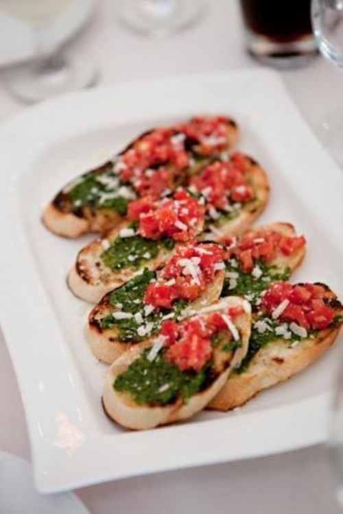 crostini topped with pesto, tomatoes and cheese are an adorable and delicious wedding appetizer iddea for summer and fall weddings