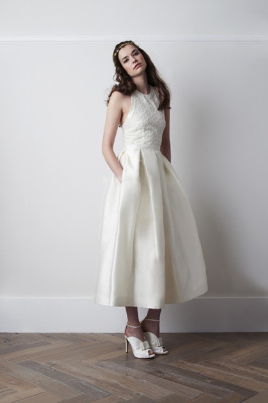 An A line midi wedding dress with a lace bodice and a plain pleated skirt plus pockets