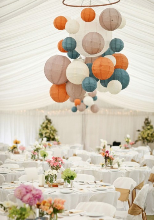 a cluster of paper pendant lamps of white, orange, greige and blue, of different sizes is a lovely idea for a wedding reception, it will add a bit of color