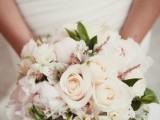 a pretty pastel wedding bouquet of blush and white blooms and some greenery plus textural elements