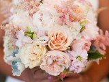 a pastel wedding bouquet of peachy, blush and neutral blooms and some greenery for a spring or summer wedding