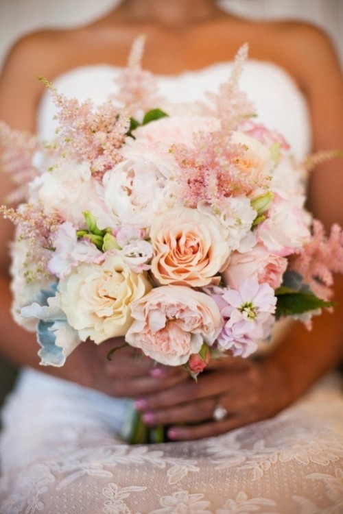 a pastel wedding bouquet of peachy, blush and neutral blooms and some greenery for a spring or summer wedding