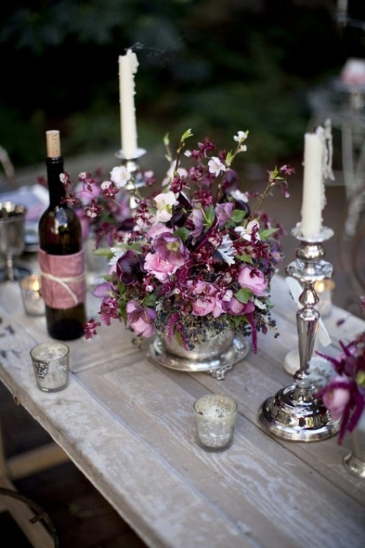 a lovely relaxed wedding tablescape with a plum and lilac colored floral centerpiece and candles is a chic idea for a fall wedding