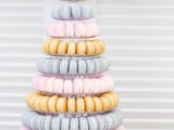 a pretty pastel pink, blue and yellow macaron tower with a clear stand is a gorgeous idea for a modern spring or summer wedding