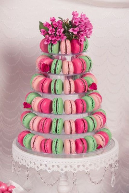 a super colorful and lovely macaron tower that includes light and hot pink plus green macarons, bold pink blooms on top is an amazing idea for a summer wedding