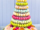 a super colorful macaron tower surrounded with bold blooms and fruits is a gorgeous and fab idea for a colorful or tropical wedding