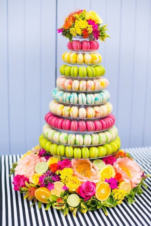 a super colorful macaron tower surrounded with bold blooms and fruits is a gorgeous and fab idea for a colorful or tropical wedding