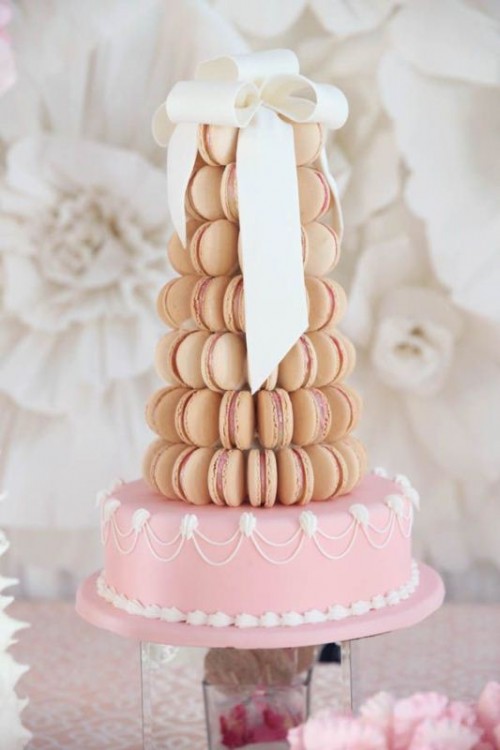a pastel wedding cake with macarons - a tan macaron tower plus a white sugar bow, a pink cake with white sugar detailing for a super glam wedding
