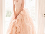 a strapless blush wedding ballgown with a draped bodice and a layered skirt plus a matching headpiece for a vintage-inspired look