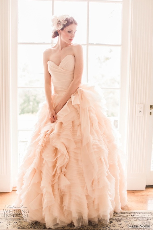 A strapless blush wedding ballgown with a draped bodice and a layered skirt plus a matching headpiece for a vintage inspired look