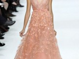 a peachy pink A-line wedding dress with a deep neckline, embellishments and floral appliques is a lovely and chic idea to rock