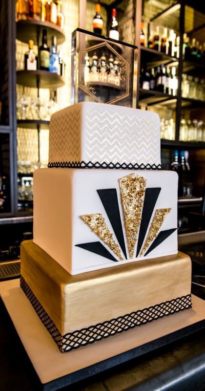 a glam and chic square wedding cake in white, gold and black, with bold art deco detailing is a gorgeous idea for a Great Gatsby party