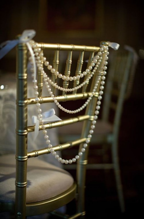 a layered pearl garland with delicate bows is a beautiful and chic decoration for a wedding chair instead of a usual plaque