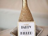 a gold glitter champagne bottle with a tag and a box is a lovely idea for a glam 1920s rehearsal dinner or wedding