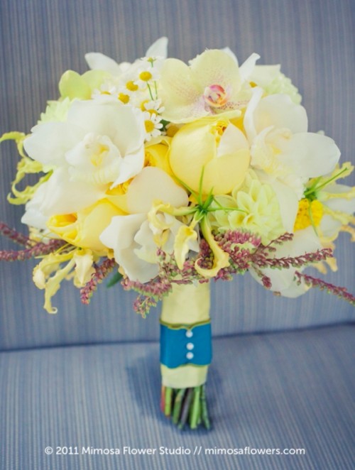 a pale yellow wedding bouquet of orchids, roses, billy balls, mimosas, chamomiles and amaranthus is a catchy idea for spring and summer