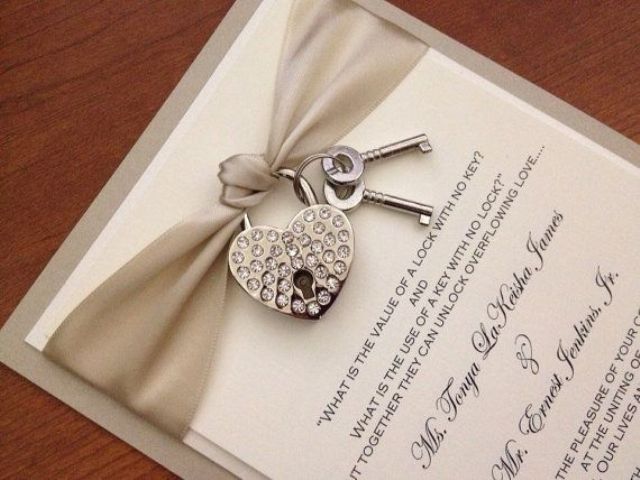 A neutral wedding invitation with a silver ribbon and an embellished lock and key is a beautiful idea for a vintage wedding