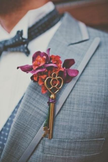 a bright wedding boutonniere of bold jewel-tone blooms and a vintage key is a cool accessory that brings color and interest to the look